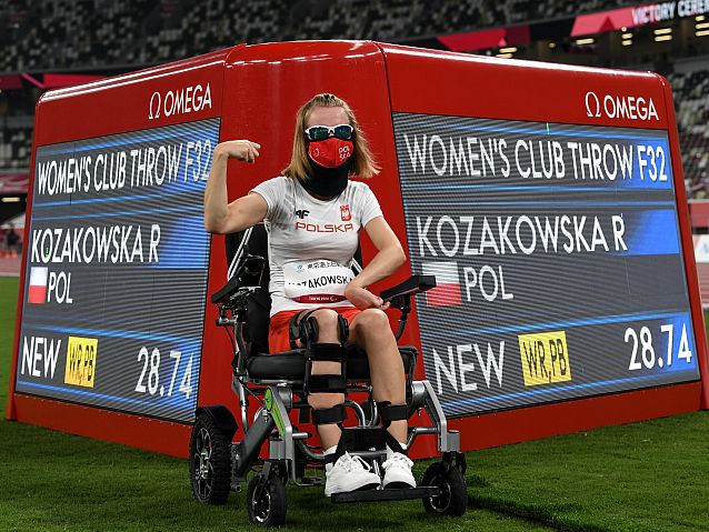Uradowana Róża Kozakowska pozuje na tle tablicy świetlnej z jej nowym rekordem świata w rzucie maczugą 28,74 m