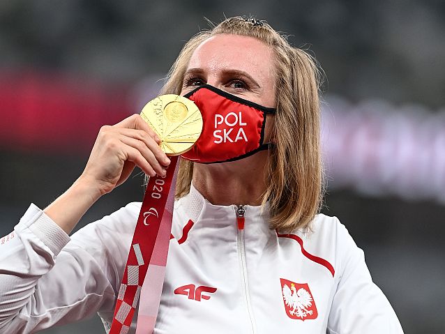 Róża Kozakowska w stroju reprezentantki Polski całuje medal przez maseczkę z napisem: Polska