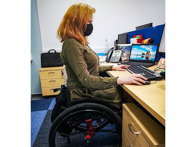dziewczyna na wózku pracuje przy biurku na komputerze