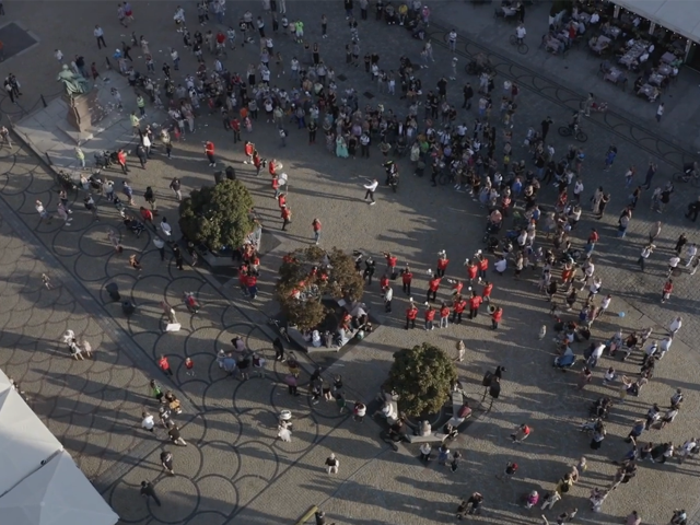 tłum osób na wrocławskim rynku, część z nich jest w czerwonych koszulkach i gra na instrumentach lub śpiewa, reszta osób przygląda się