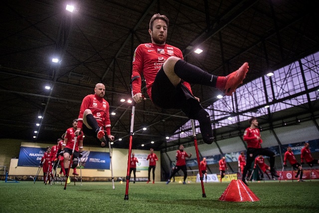 starsza kadra ampfutbolistów ma trening. ćwiczą, mają nogę lub 1,5 nogi w górze, ręce proste w łokciach, podparci na kulach