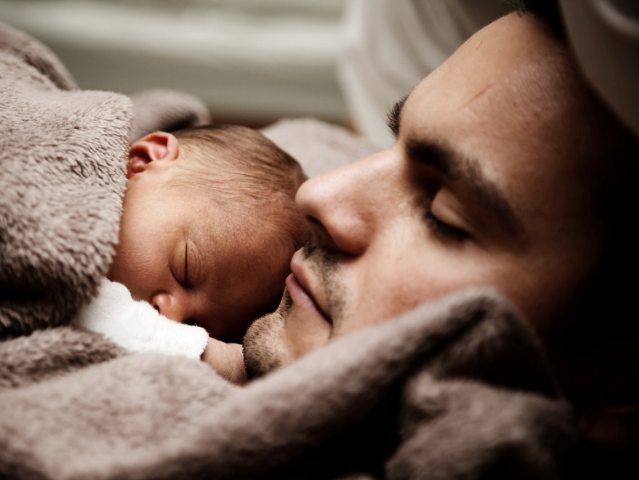 niemowlę śpi przy syi śpiącego młodego mężczyzny