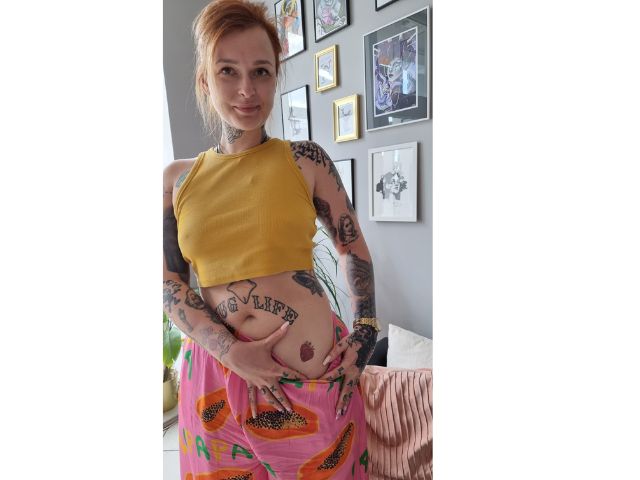 Młoda rudowłosa kobieta pokazująca swój tatuaż.
