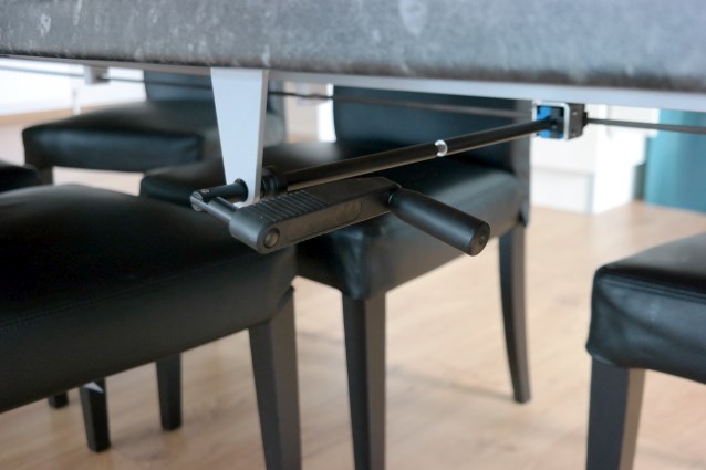 pod stołem znajduje się mechanizm - rączka, którą trzeba kręcić, dzięki któremu można zmienić wysokość stołu