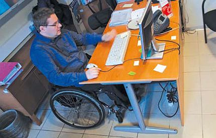 Mężczyzna na wózku siedzi przy komputerze