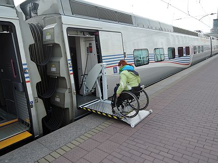 Osoba na wózku wjeżdża po pochylni do pociągu