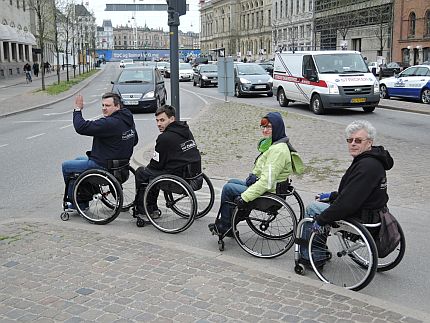 Cztery osoby na wózkach przejeżdżają przez przejście dla pieszych