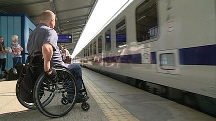 Mężczyzna na wózku stoi na peronie przed pociągiem