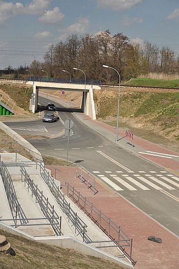 Fragment podjazdu z widokiem na chodnik i ulicę z samochodami.