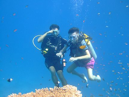 Autor nurkujący w błękitnej wodzie Morza Czarnego w asyście mężczyzny, pod nimi rafa koralowa, naokoło małe kolorowe rybki