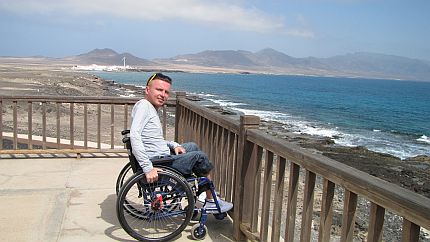 Autor stoi na wózku na tarasie z widokiem na ocean
