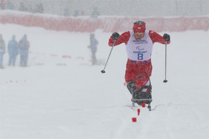 Kamil Rosiek przebija się na sledżu przez śnieg podczas biegu narciarskiego