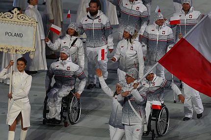 Reprezentanci Polski idą machając flagami na stadionie podczas otwarcia igrzysk w Soczi.