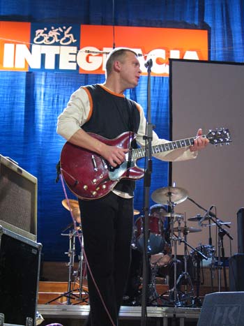Mężczyzna z gitarą na scenie, w tle napis Integracja