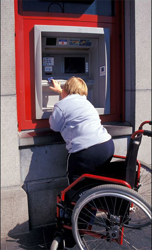 Kobieta na wózku korzystająca z bankomatu. Fot.: East News